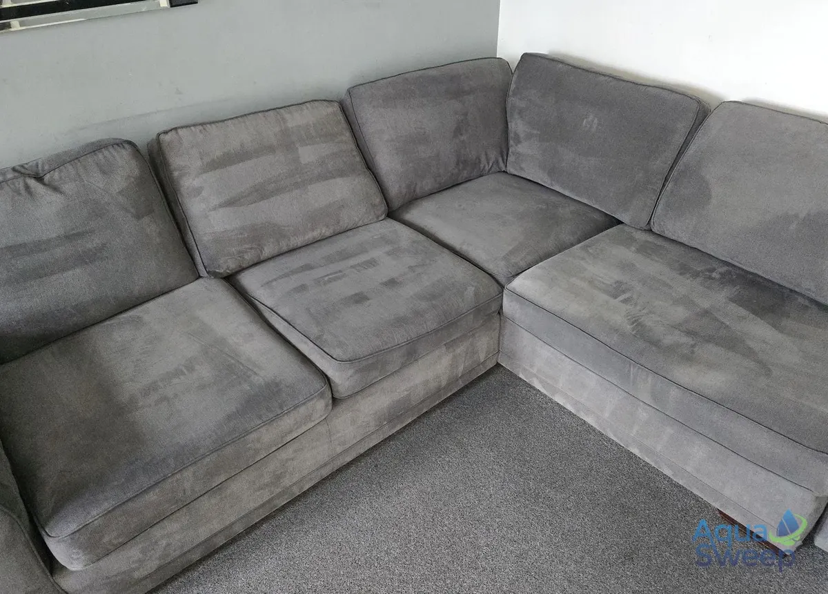 After: grey fabric corner sofa with dark water marks across the seats