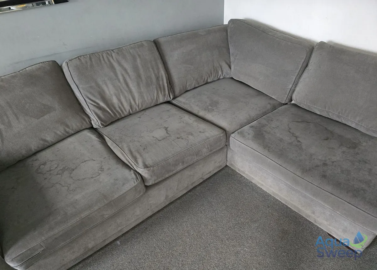 Before: grey fabric corner sofa with dark water marks across the seats