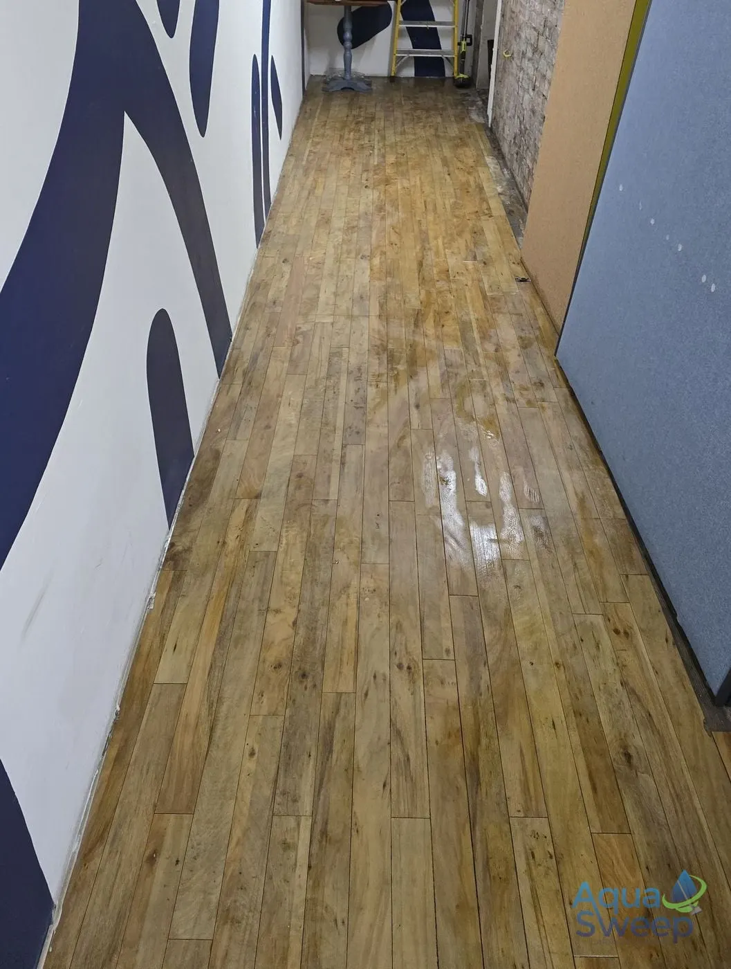 After: dull, grubby wood effect LVT floor in a long corridor