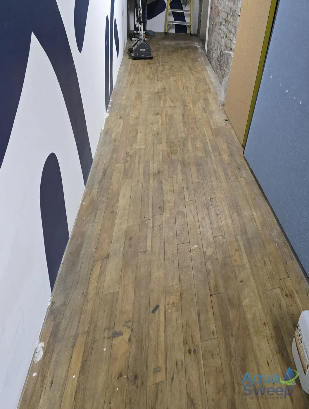Before: dull, grubby wood effect LVT floor in a long corridor