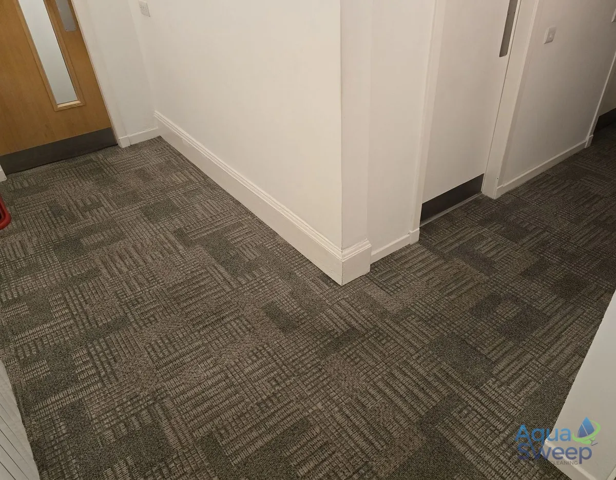 After: office carpet tiles in a corridor corner, darkened by foot traffic