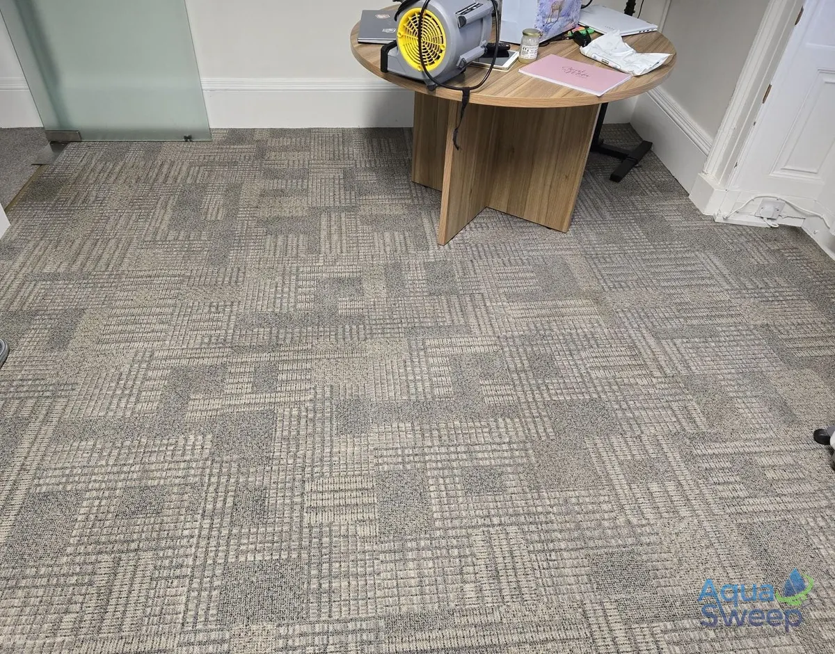 After: patterned office carpet tiles with dirt and marks across a meeting room