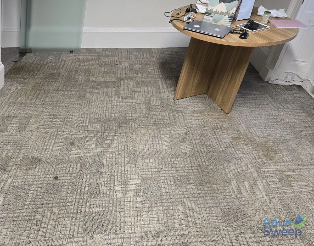 Before: patterned office carpet tiles with dirt and marks across a meeting room