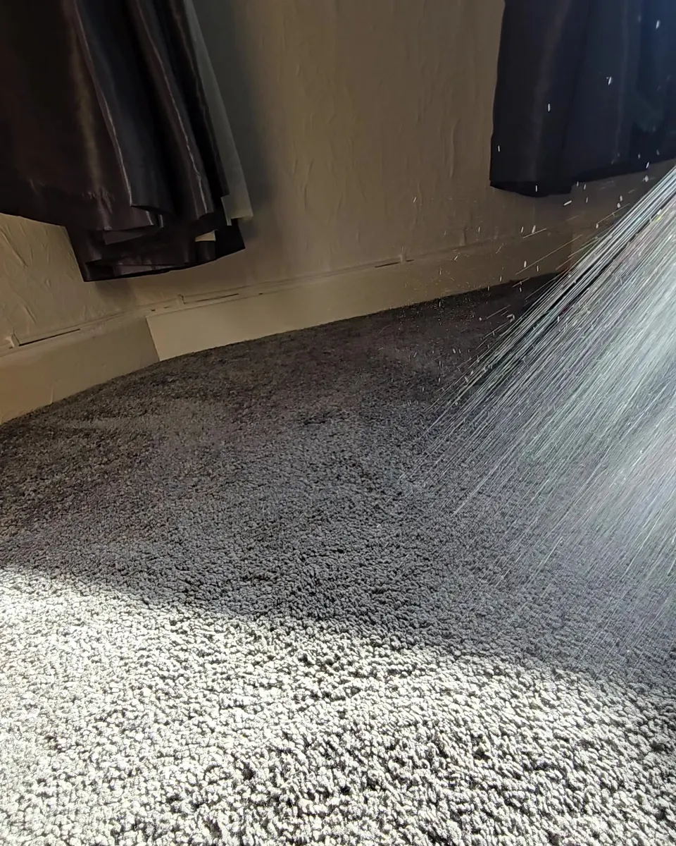 Pre clean solution being sprayed across a grey carpet