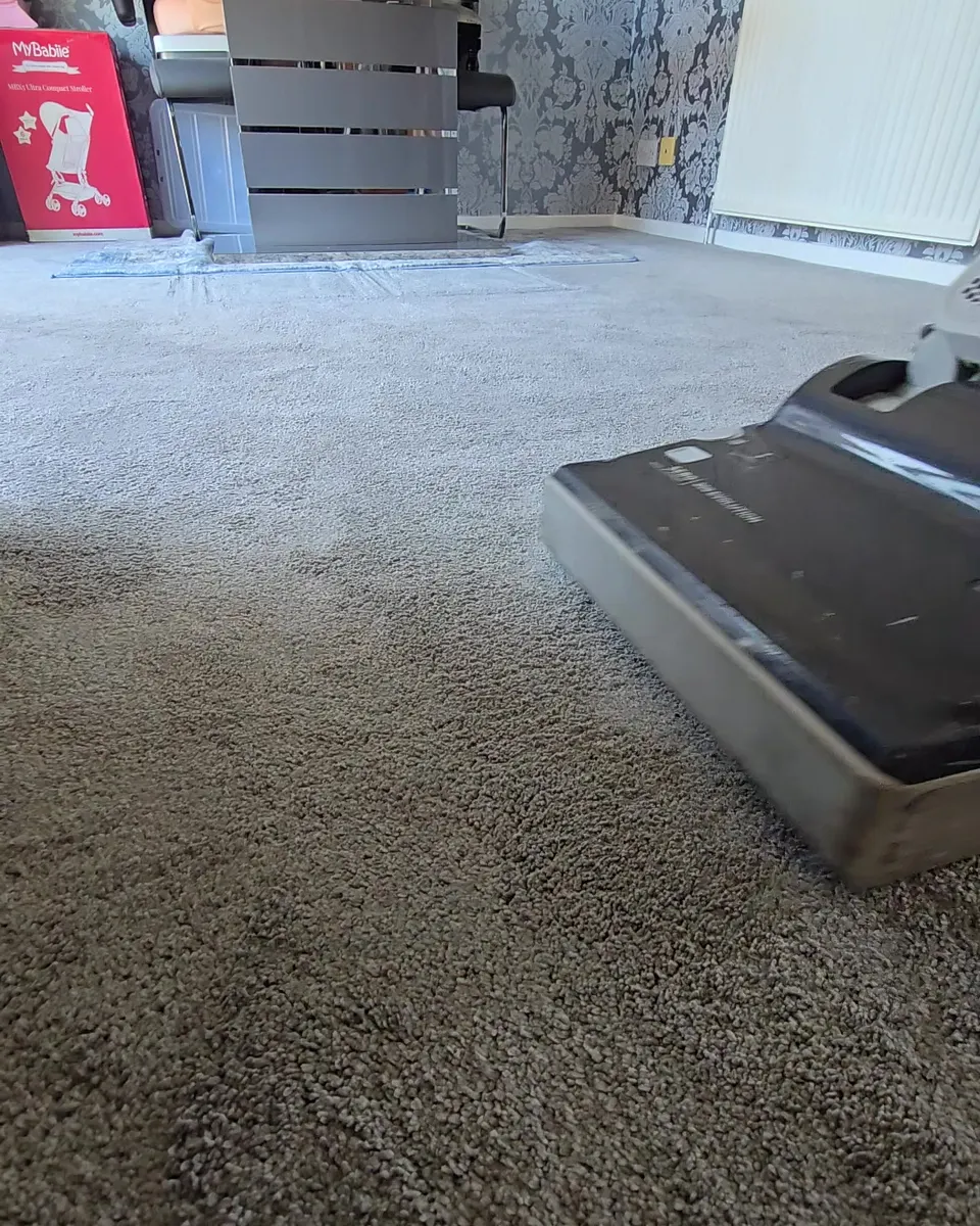 Upright vacuum going over a light brown carpet before cleaning