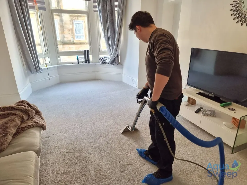 Cleaning a living room carpet with a wand in a Glasgow tenement flat