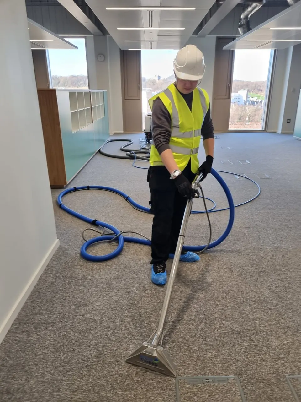 AquaSweep team member in hi-vis cleaning an office carpet with a wand
