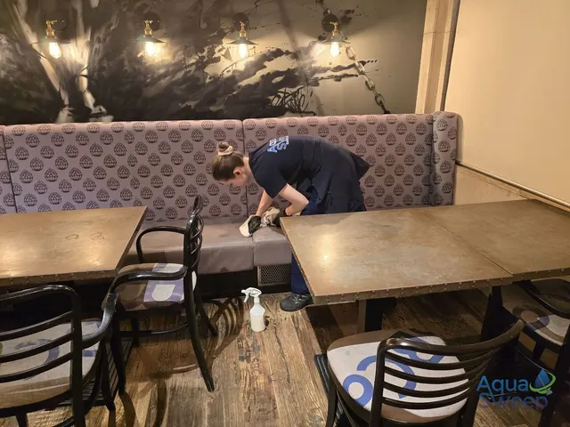 Cleaning the fabric booth seating in a restaurant