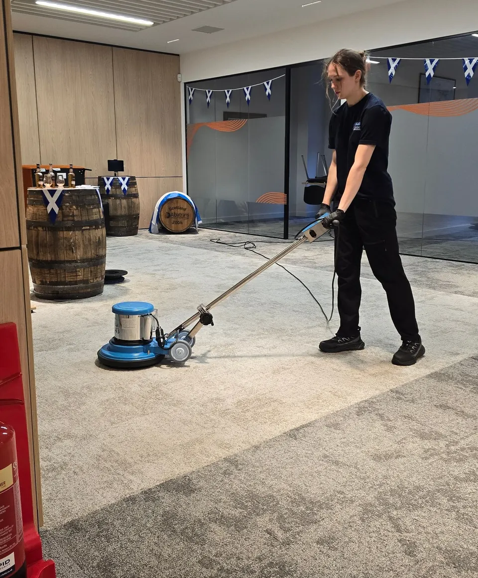AquaSweep team member cleaning an office carpet with a floor machine