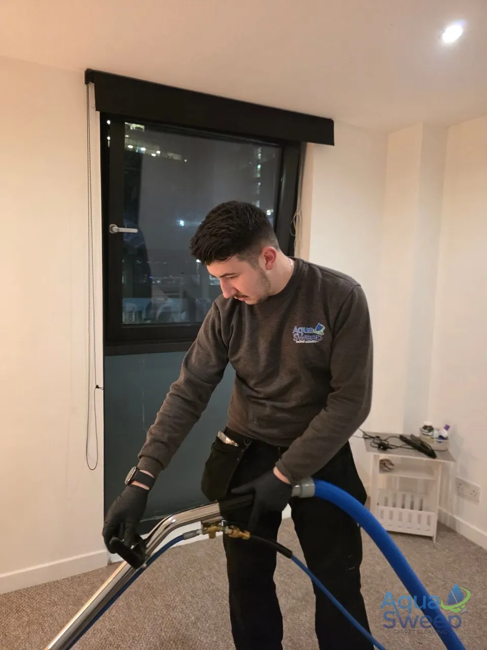 Carl cleaning a bedroom carpet with a wand in the evening